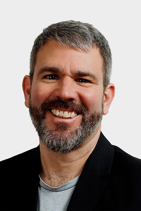 Porträt eines Mannes mit schwarz-grauen Haaren und Bart.